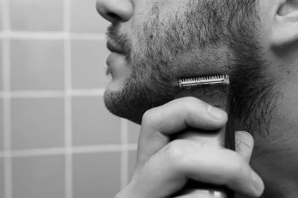 Porträt eines jungen Mannes, der sich mit Trimmer rasiert — Stockfoto