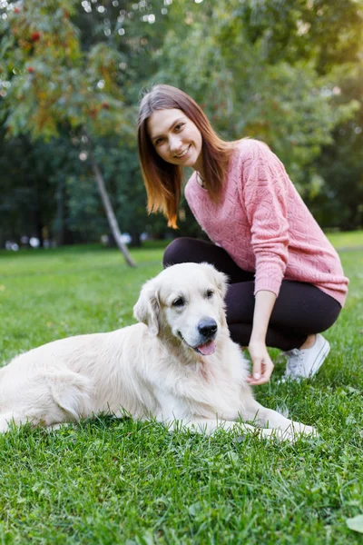 Image of woman with dog lying on lawn in summer park