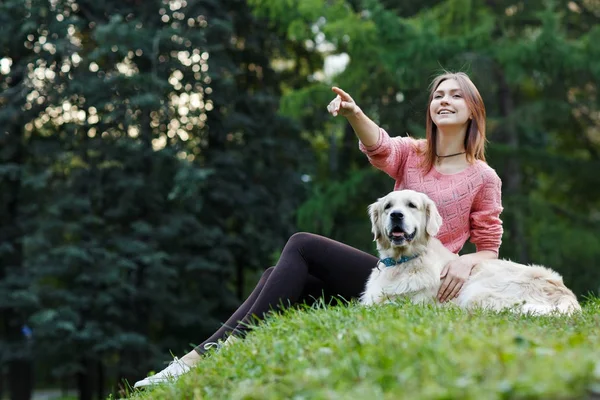 Uit onderstaande afbeelding van woman wijzend naar voren naast hond op groen gazon — Stockfoto