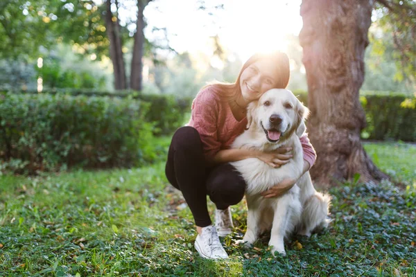 Foto einer Frau, die Hund auf Rasen umarmt — Stockfoto