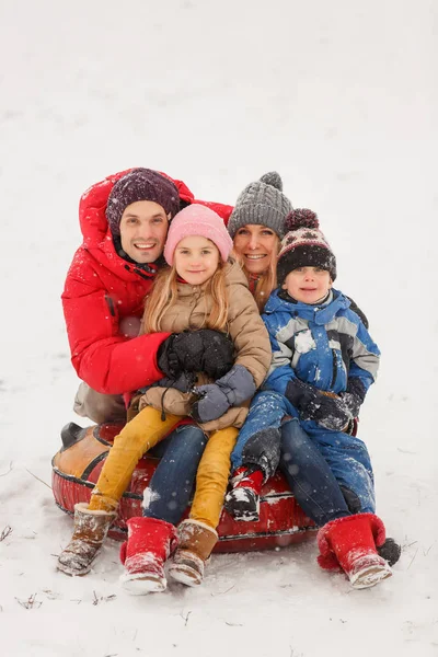 Изображение счастливой семьи с дочерью и сыном, сидящими на трубах зимой — стоковое фото
