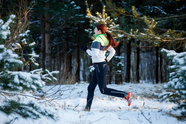 Fiatal nő sportoló fut át téli erdő képe — Stock Fotó