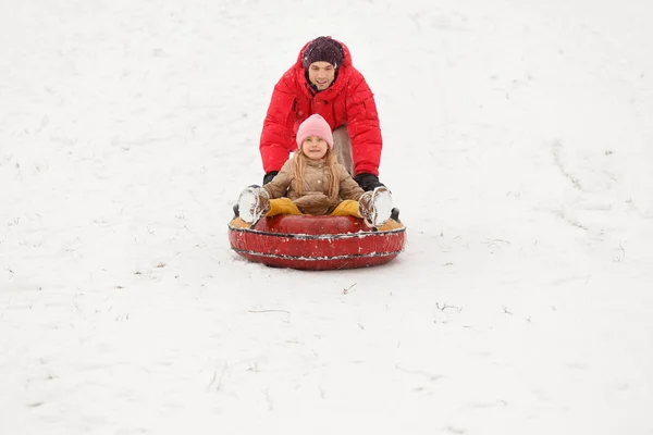 Photo de père et fille en promenade avec tubulure dans le parc d'hiver — Photo