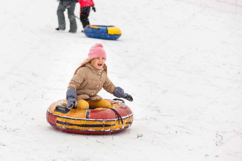 Image of happy girl riding tubing in winter park