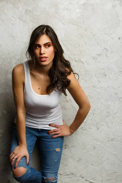 Picture of beautiful brunette in white tank top and ripped jeans — Stock Photo, Image