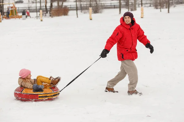 Image of father skating daughter on tubing in winter afternoon — Stock Photo, Image