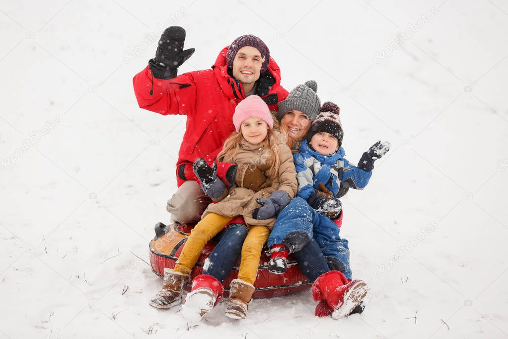 Picture of happy parents with daughter and son sitting on tubing in winter