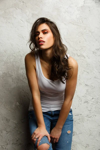 Imagen de hermosa morena en camiseta blanca y jeans rasgados —  Fotos de Stock