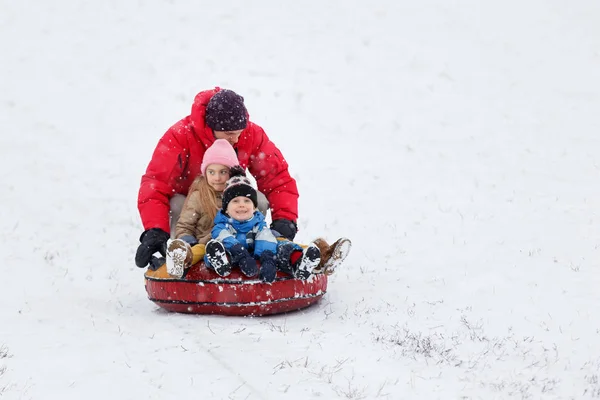 Photo de père, fille et fils heureux sur tube dans le parc d'hiver — Photo