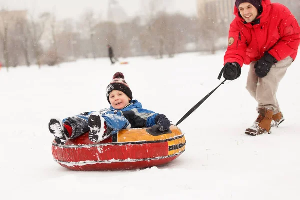 Photo de joyeux père patinage fils sur tube dans l'après-midi d'hiver — Photo