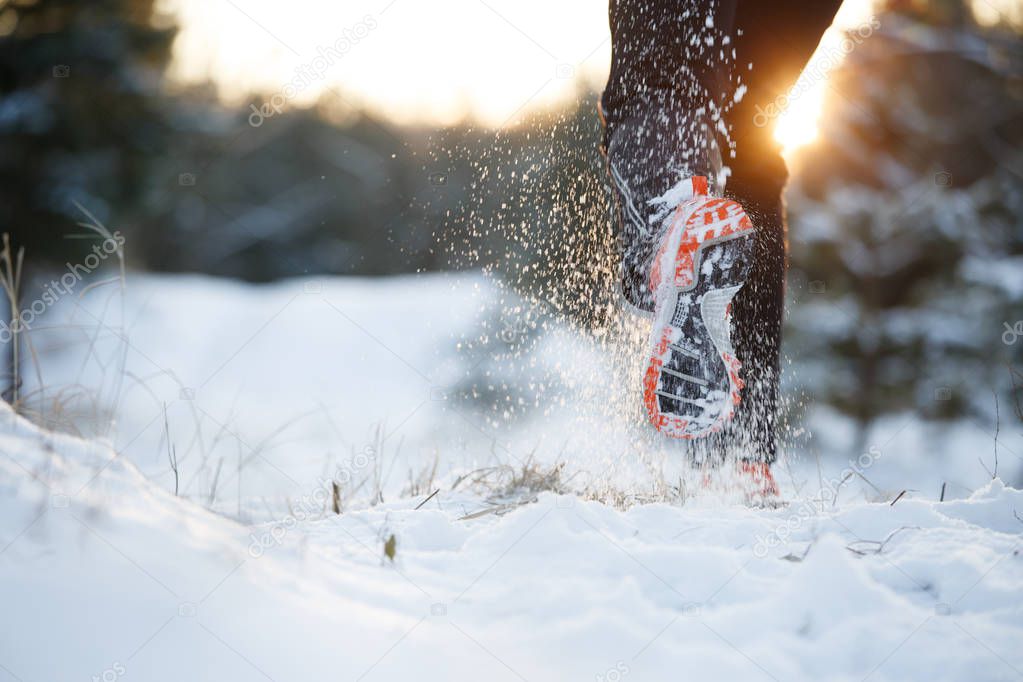 Image of running man in sneakers on snowy forest in winter