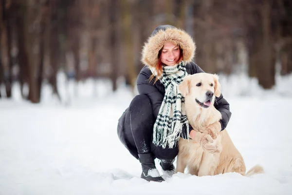 Foto van meisje in een zwarte jas gehurkt naast de hond in de winter — Stockfoto