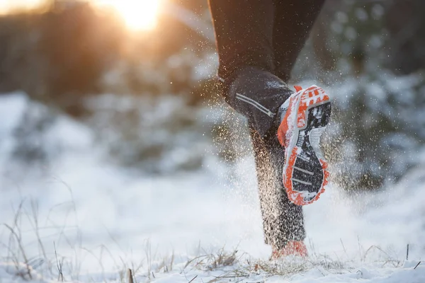 Photo of running man running in sneakers on snowy forest