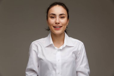 Güzel kız Beyaz gömlekli duygular - gülümseme, eğlenceli gösterir. Hafif bir arka plan üzerinde.