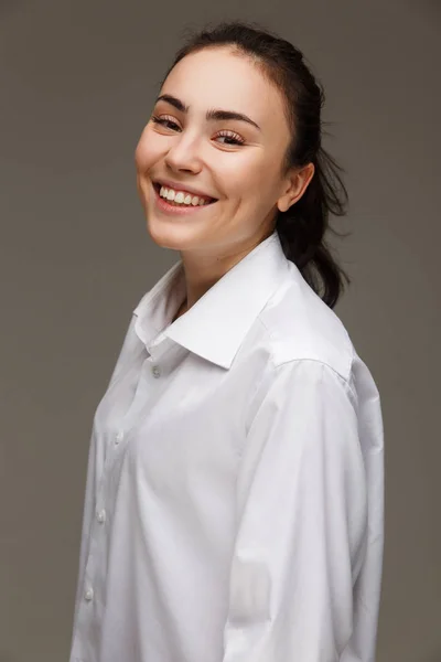 Beautiful girl in a white shirt shows emotions - smile, fun. On a light background. — Stock Photo, Image