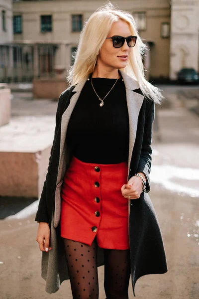 Modemädchen in modischer Kleidung. schönes Mädchen in Mantel und rotem Rock. Posieren auf der Straße — Stockfoto