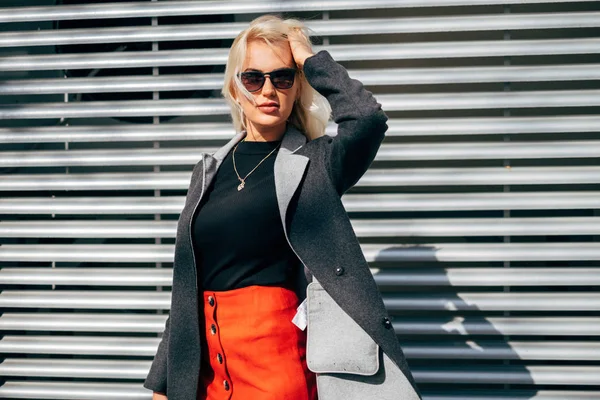 Chica de moda en ropa de moda. Hermosa chica con un abrigo y una falda roja. Posando en la calle — Foto de Stock