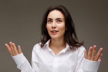 Güzel kız Beyaz gömlekli duygular - sürpriz, şok, hafif bir arka plan üzerinde gösterir..