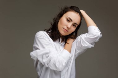 Beyaz bir gömlek güzel kız kendini kucaklar. Hafif bir arka plan üzerinde.