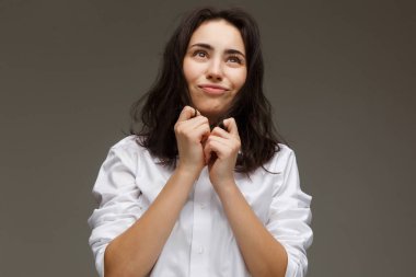 Güzel kız Beyaz gömlekli duygular - eğlenceli gösterir. Hafif bir arka plan üzerinde.