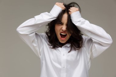 Güzel kız Beyaz gömlekli duygular - sürpriz, şok, hafif bir arka plan üzerinde gösterir..