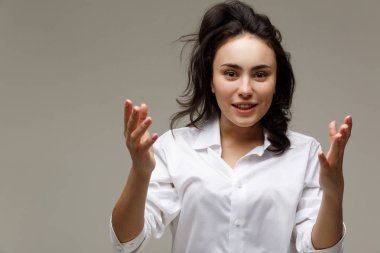 Güzel kız Beyaz gömlekli duygular - sürpriz, şok, hafif bir arka plan üzerinde gösterir..