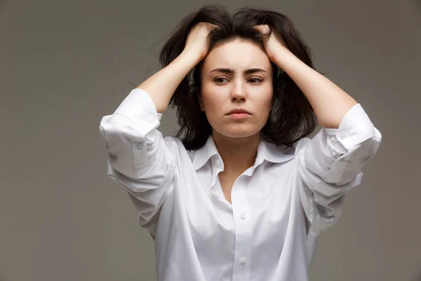 Hermosa chica en una camisa blanca muestra emociones - reflexividad. Sobre un fondo claro . — Foto de Stock