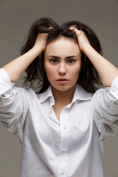 Hermosa chica en una camisa blanca muestra emociones - reflexividad. Sobre un fondo claro . — Foto de Stock