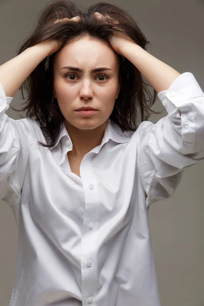 Hermosa chica en una camisa blanca muestra emociones - reflexividad. Sobre un fondo claro . — Foto de Stock