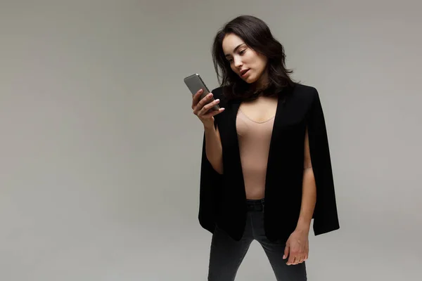 Красивая модная женщина в джинсах и пиджаке. с телефоном в руках — стоковое фото