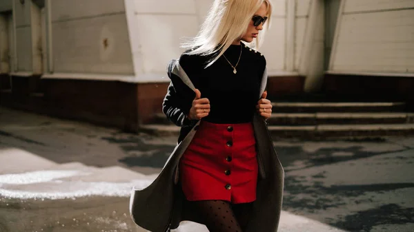 Chica de moda en ropa de moda. Hermosa chica con un abrigo y una falda roja. Posando en la calle — Foto de Stock