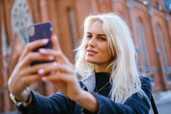 Fashion Girl In Fashionable Clothing. Beautiful girl in a coat and a red skirt. does selfie — Stock Photo, Image