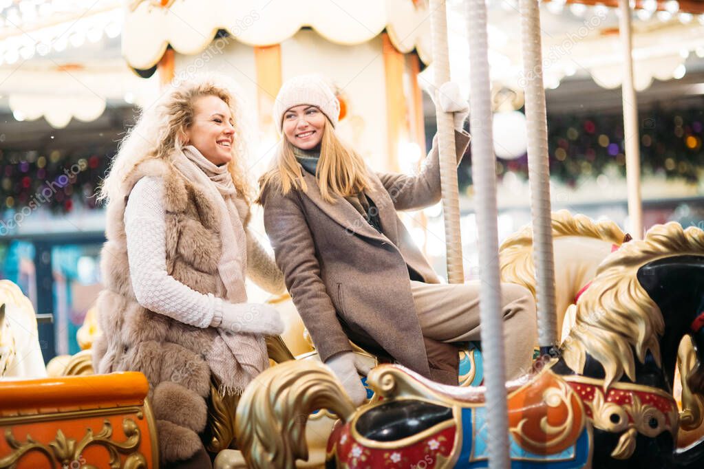 Photo of two women riding on carousel in park