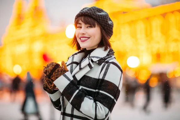 Bild der jungen Brünetten mit Hut und kariertem Mantel beim Winterspaziergang. — Stockfoto