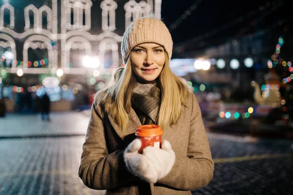 Frau mit Glas in der Hand auf der Straße vor dem Hintergrund eines Gebäudes mit Girlanden. — Stockfoto