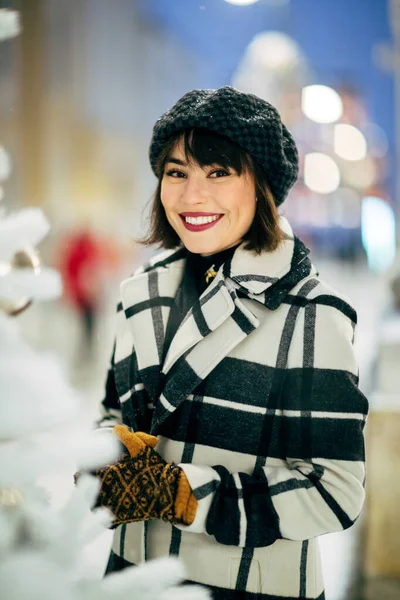 Zdjęcie szczęśliwej brunetki w pobliżu białej sztucznej choinki na spacerze po ulicy — Zdjęcie stockowe