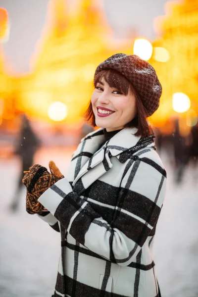 Bild der jungen Brünette mit Hut und kariertem Mantel auf Winterspaziergang. — Stockfoto