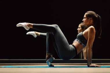 Spor salonundaki halının üzerinde uzanan genç bayan.