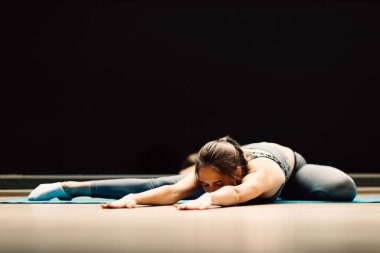 Spor salonunda halının üzerinde uzanan atletik kadın.