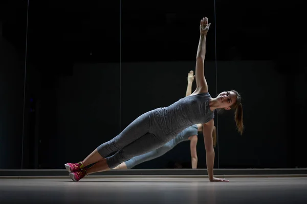 Jonge sportvrouw in grijs sportpak in stretching training — Stockfoto