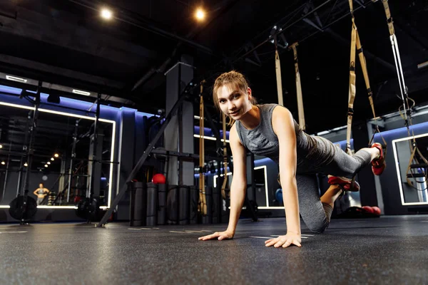 Fiatal atlétikai nő nyújtózkodik rugalmas szalagok tornaterem — Stock Fotó