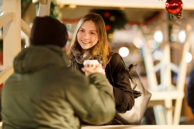 Arkadan bir adam ve sokak kafesinde gözlüklü bir kadın.