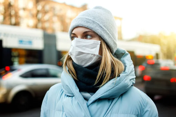 Blonde in mask is standing next to bus for walk on street in city during day. — Stock Photo, Image
