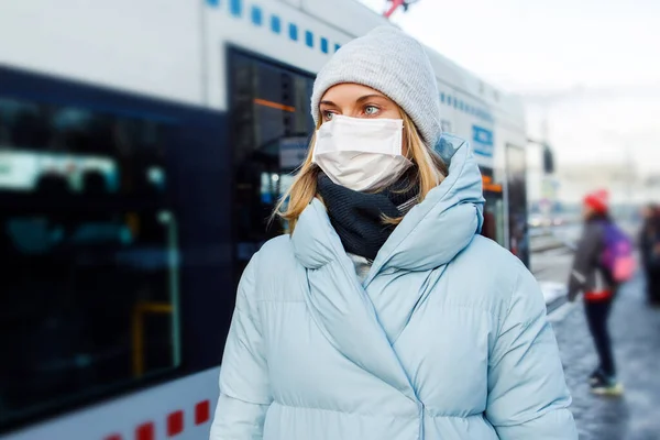 Молодая женщина в маске стоит рядом с автобусом для прогулок по улице в течение дня . — стоковое фото