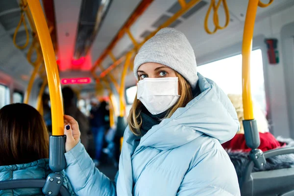 Rubia en máscara médica de pie en el salón de autobuses junto a pasamanos amarillos por la tarde . —  Fotos de Stock