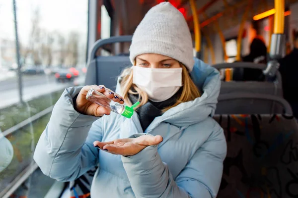 Жінка в масці дезінфікує руки інструментом, сидячи на автобусі біля вікна — стокове фото