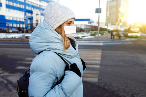 Young woman in mask on walk on street in city during day.