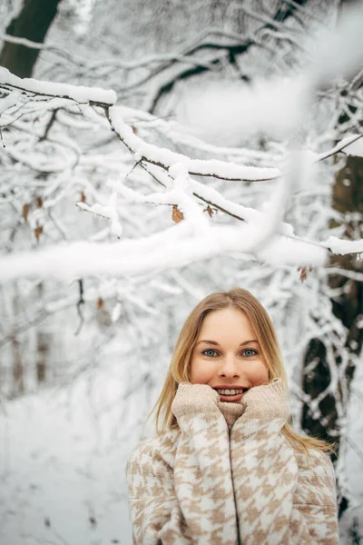 Donna felice con le palme vicino al viso sullo sfondo di alberi innevati per camminare nella foresta invernale — Foto Stock