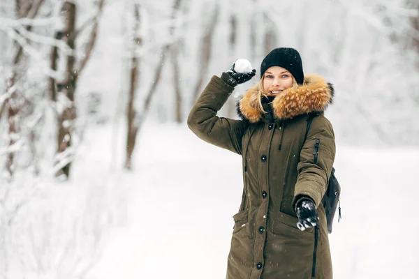 Ung flicka med snö i händerna på promenad i vinterskogen — Stockfoto