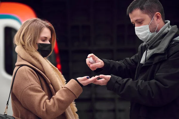 Молодий чоловік і жінка в медичних масках використовують антисептик, стоячи біля підземних перевезень . — стокове фото